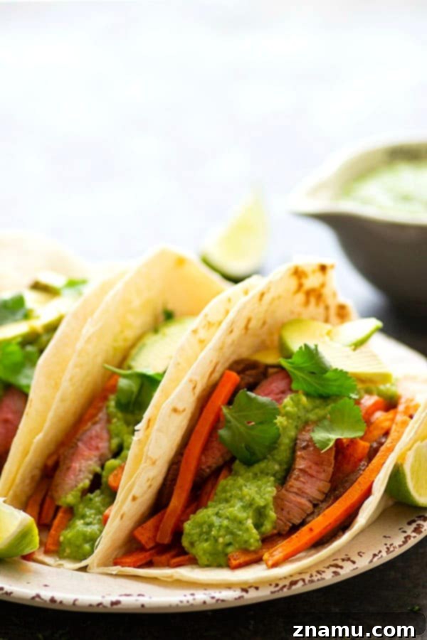Jerk Sweet Potato Tacos with Zesty Avocado Tomatillo Salsa 5 Jerk Sweet Potato Steak Tacos - A close-up of a hand preparing a Jerk Sweet Potato Steak Taco, adding fresh cilantro and a dollop of creamy avocado salsa verde on top.