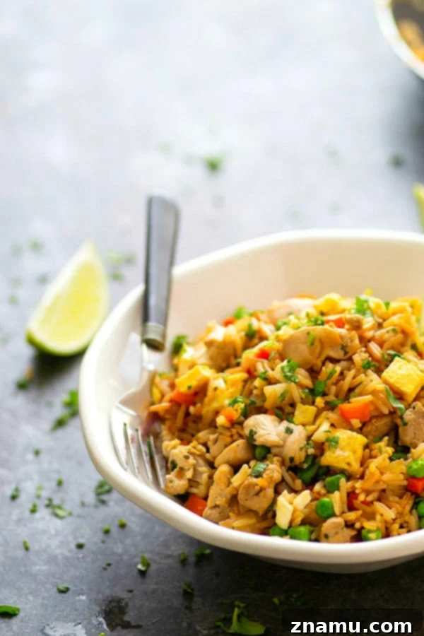 Herby Citrus Chicken Fried Rice 5 A large serving spoon scooping Cilantro Lime Chicken Fried Rice from a pan, showing the rich texture and delicious ingredients.