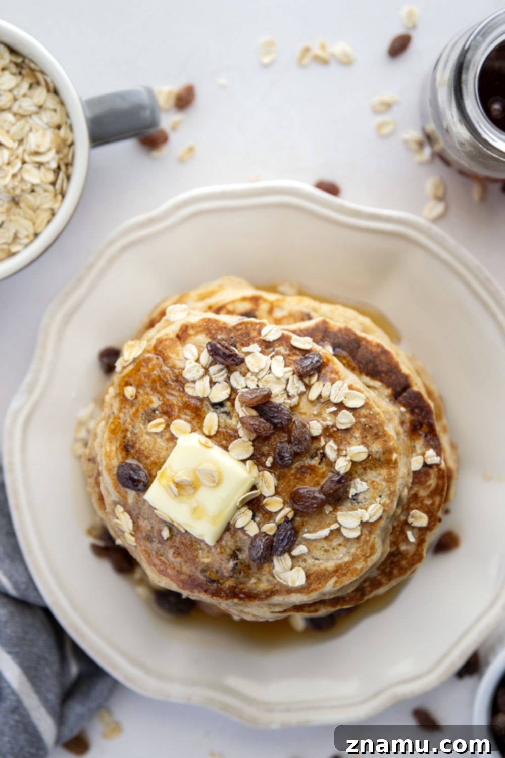 Wholesome Oat and Raisin Pancakes 3 Close-up shot of a single oatmeal raisin pancake on a plate, showcasing its fluffy interior speckled with tender oats and juicy raisins.