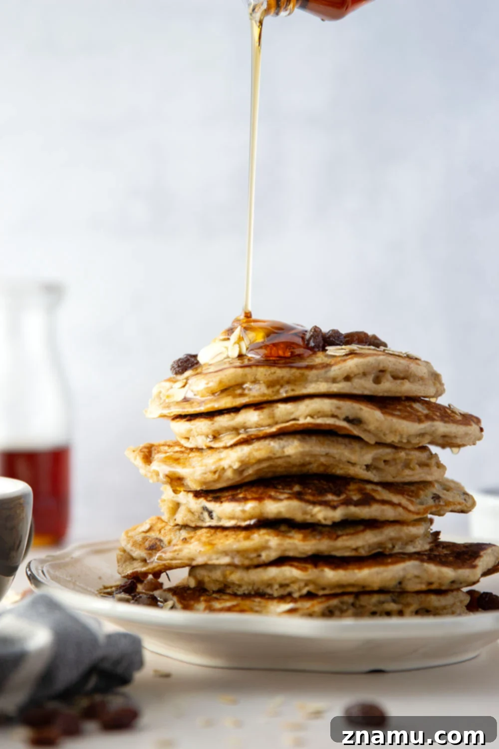 Wholesome Oat and Raisin Pancakes 4 Ingredients for oatmeal raisin pancakes laid out on a wooden counter: oats, brown sugar, flour, buttermilk, and butter.
