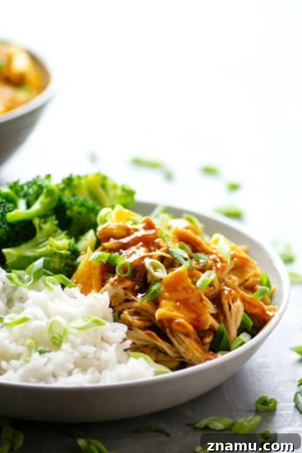 Close-up of shredded Instant Pot Orange Chicken with a rich, glossy sauce, ready to be served over rice in a healthy meal prep bowl.