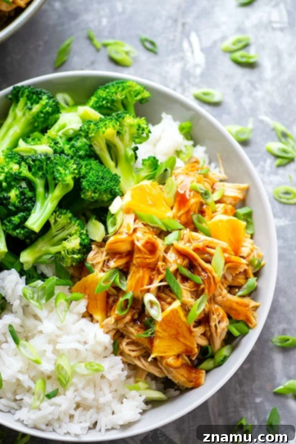 A beautifully plated Instant Pot Orange Chicken rice bowl, garnished with fresh orange wedges and green onions, showcasing a complete and healthy meal.