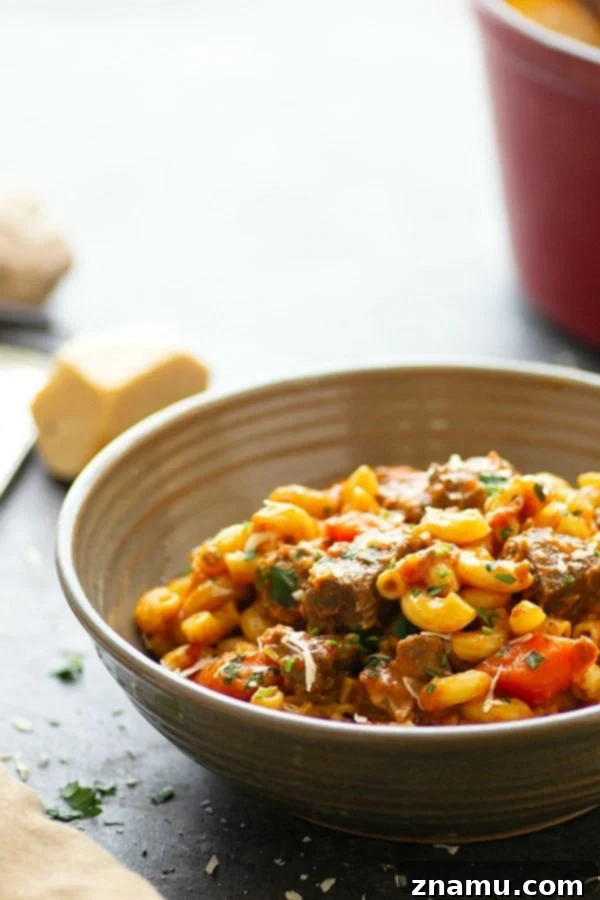 Soul-Satisfying One-Pot Beef Goulash 5 A steaming bowl of homemade one-pot beef goulash garnished with fresh parsley and a dollop of sour cream, served with crusty bread.