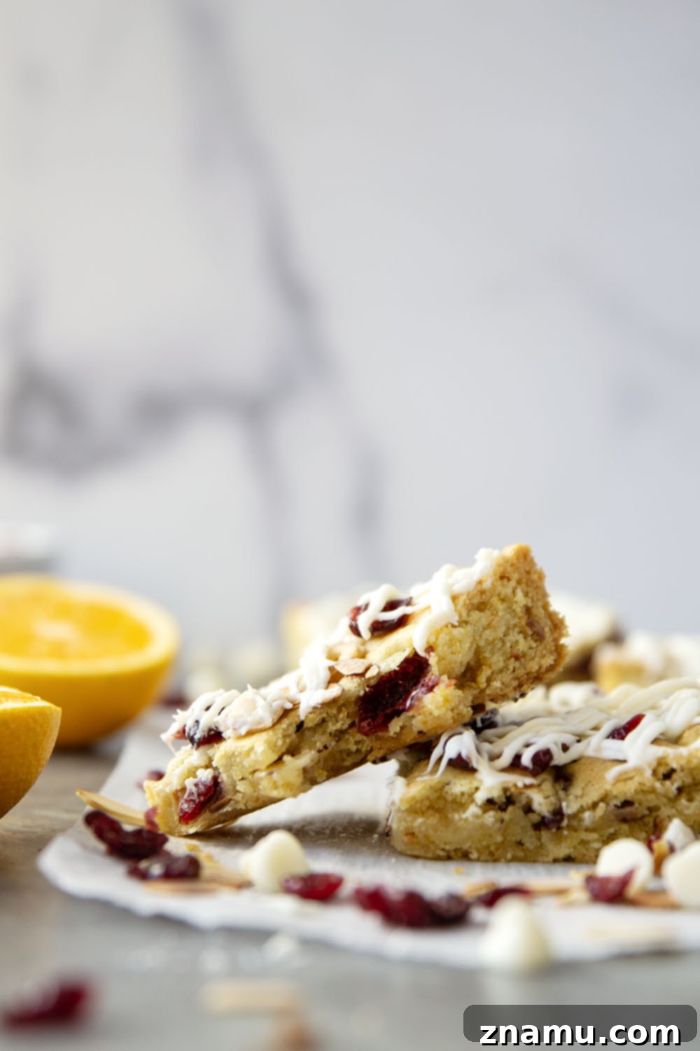 Buttery Cranberry Almond Bars 2 Close-up of a stack of soft, chewy cranberry almond bars with white chocolate drizzle, toasted almonds, and dried cranberries, perfect for holiday baking.
