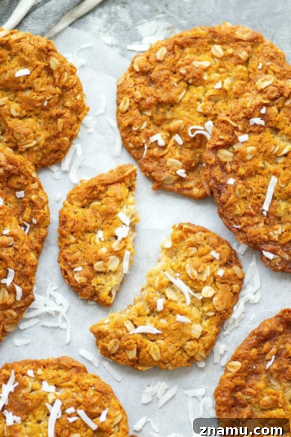 A stack of golden Anzac Biscuits on a cooling rack.