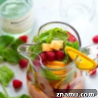 Sweet moscato sangria is livened up with the addition of fresh cantaloupe, tangy raspberries, and refreshing mint leaves.