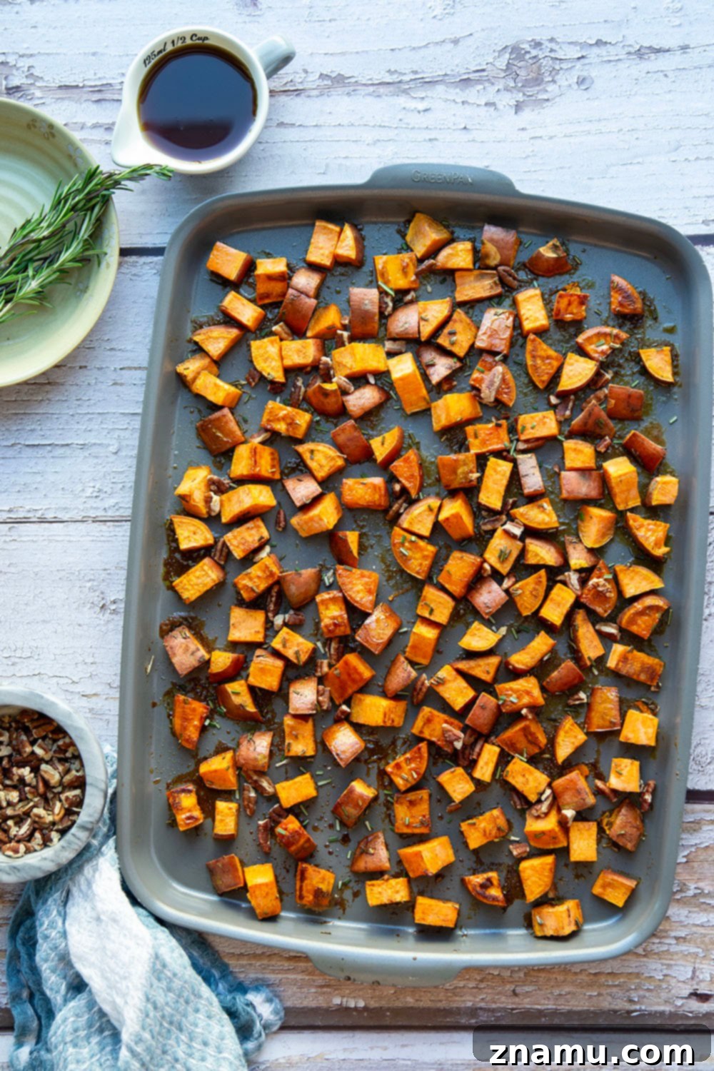 Roasted Sweet Potatoes with Maple and Rosemary 3 A serving of roasted sweet potatoes with rosemary and maple syrup, showing the tender interior and caramelized edges, on a white plate.