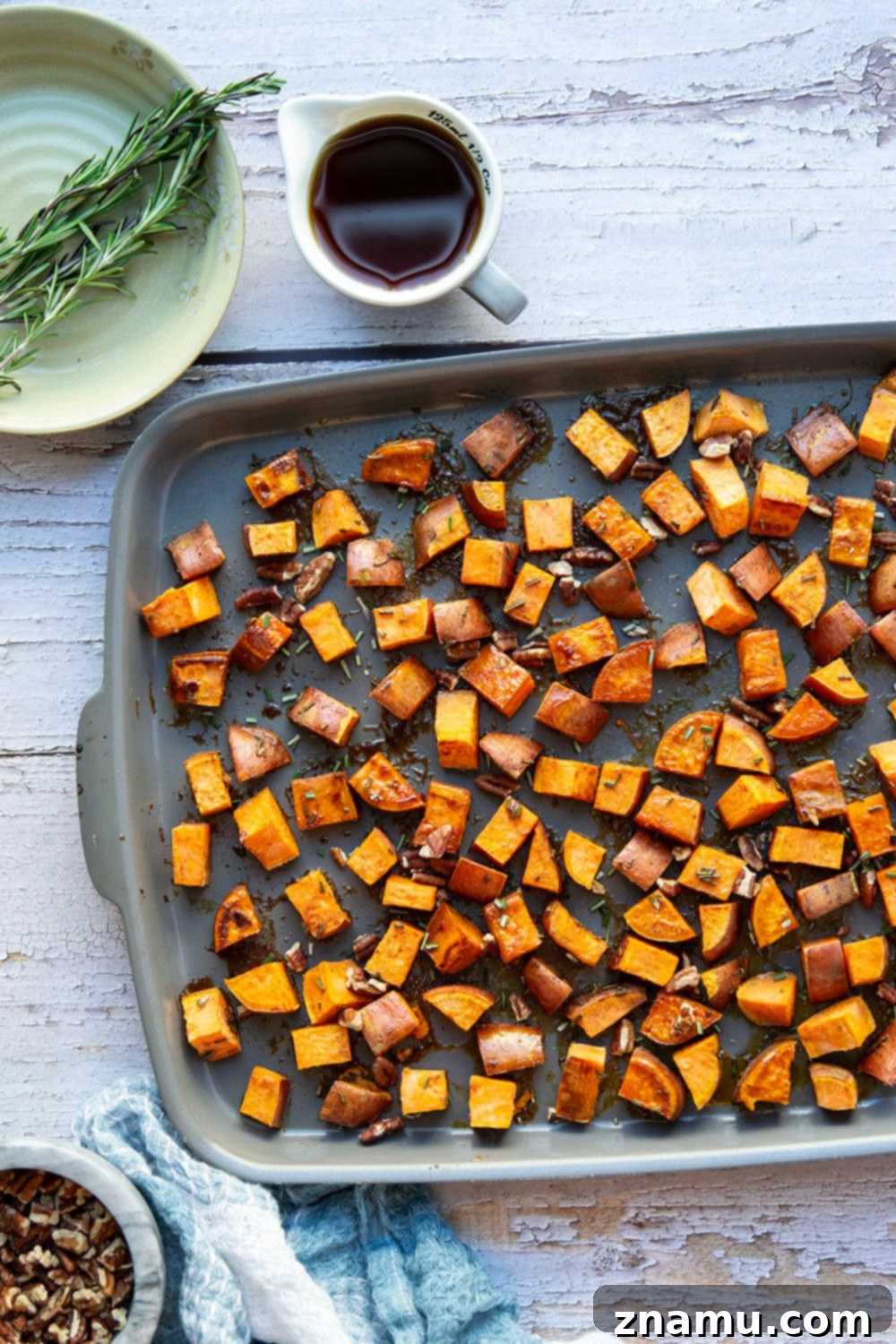 Roasted Sweet Potatoes with Maple and Rosemary 5 Sweet potato cubes tossed with olive oil, maple syrup, and fresh rosemary in a mixing bowl before roasting.