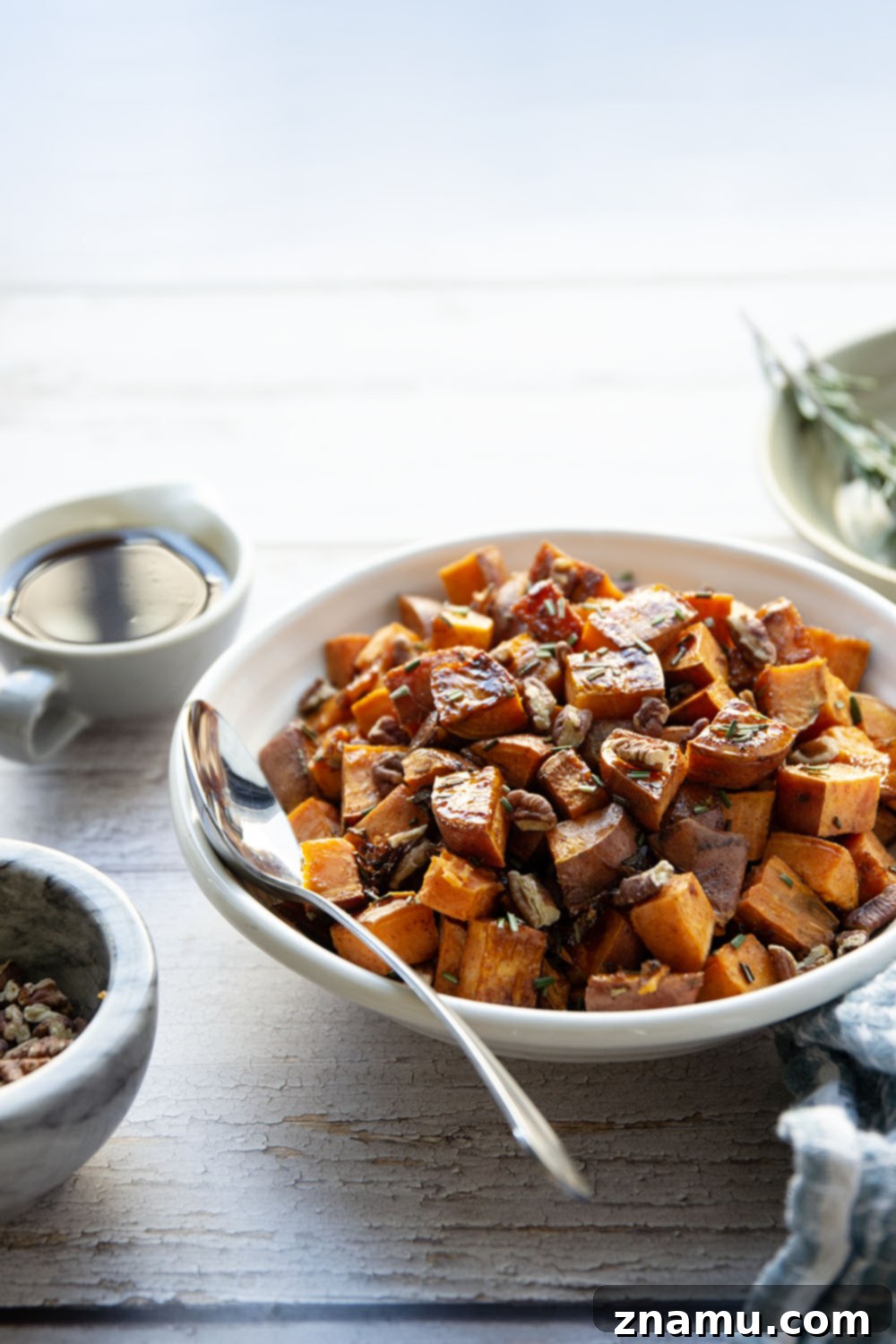 Roasted Sweet Potatoes with Maple and Rosemary 6 A large serving platter piled high with maple rosemary roasted sweet potatoes and toasted pecans, ready for a gathering.