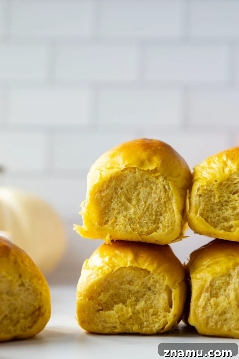 Warm Spiced Pumpkin Rolls 6 Freshly baked pumpkin dinner rolls pulled apart, revealing a soft, airy interior, ready for butter