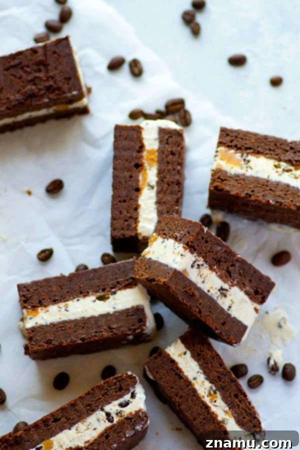 Decadent Espresso Peanut Butter Brownie Ice Cream Sandwiches 4 Hand holding a cut brownie ice cream sandwich, revealing layers of brownie, espresso ice cream, and peanut butter swirl.