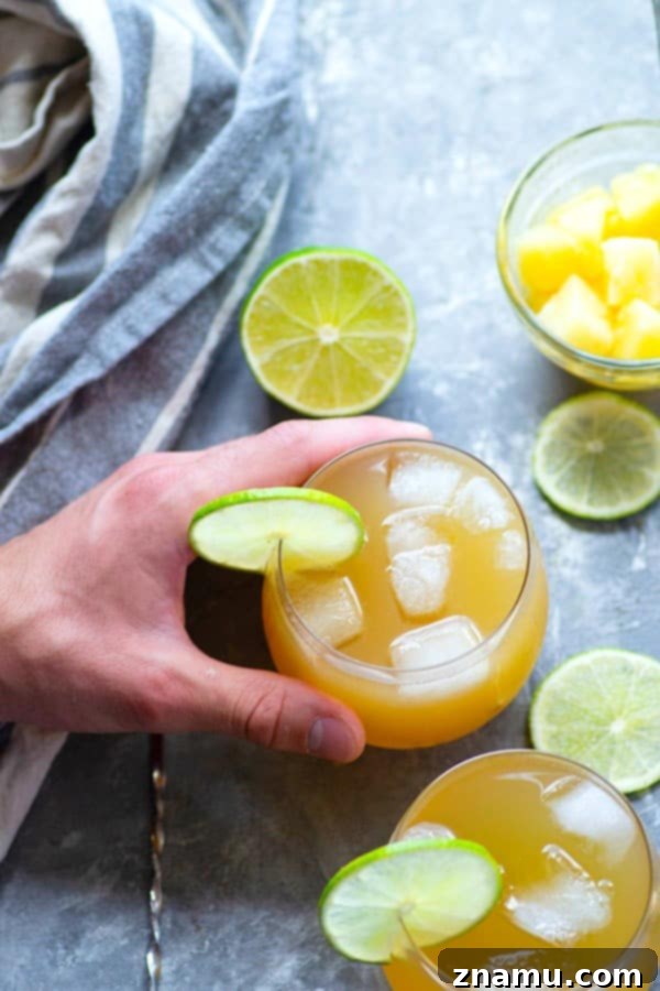 Ginger Isle Gin Spark 3 Close-up of the Pineapple Gin Cocktail with visible ice and lime slices, highlighting its refreshing appeal.