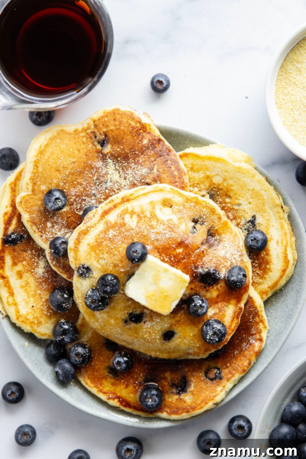 Golden Corn & Berry Flapjacks 3 Close-up of a stack of fluffy blueberry cornmeal pancakes with blueberries visible, perfectly cooked and lightly browned.
