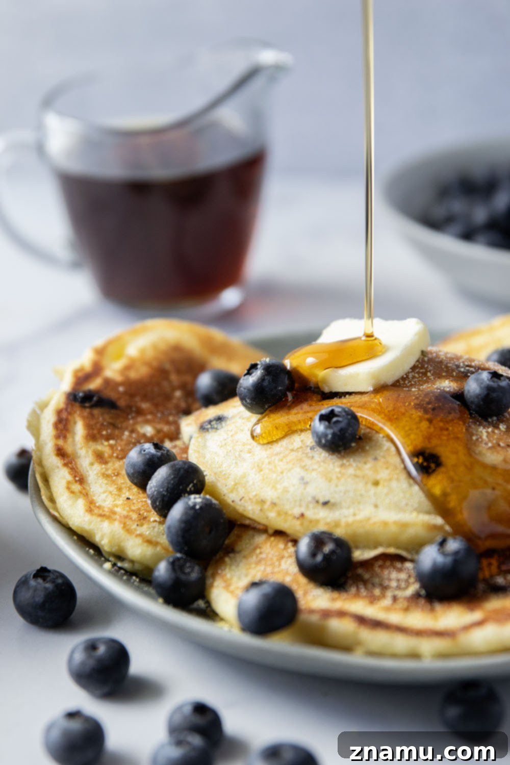 Golden Corn & Berry Flapjacks 4 A top-down view of a plate of blueberry cornmeal pancakes, showcasing their golden color and the juicy blueberries embedded within.