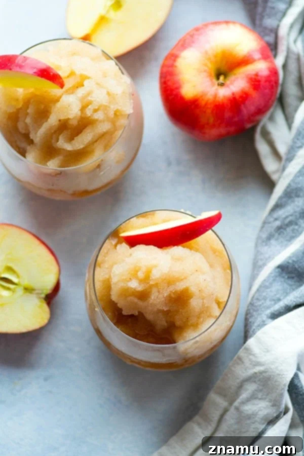 Autumn Bourbon Apple Freeze 2 Close-up of a vibrant Apple Cider Bourbon Slushie in a glass, garnished with an apple slice and cinnamon stick, evoking cozy fall vibes.