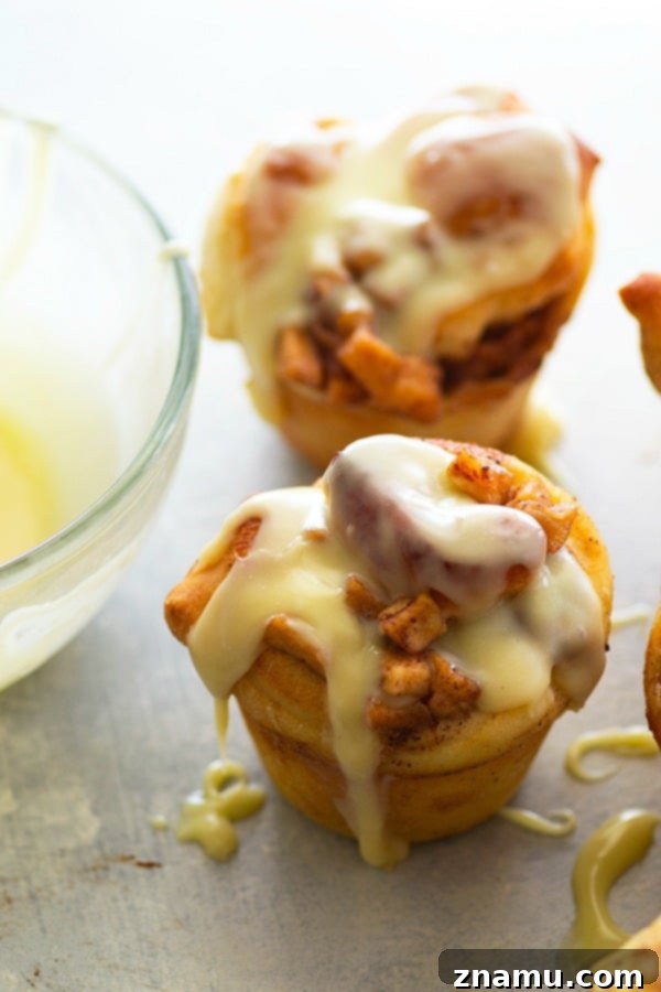 Fluffy cinnamon roll muffins are stuffed with a caramelized apple filling and glazed in a sweet white chocolate glaze for a dreamy fall breakfast!