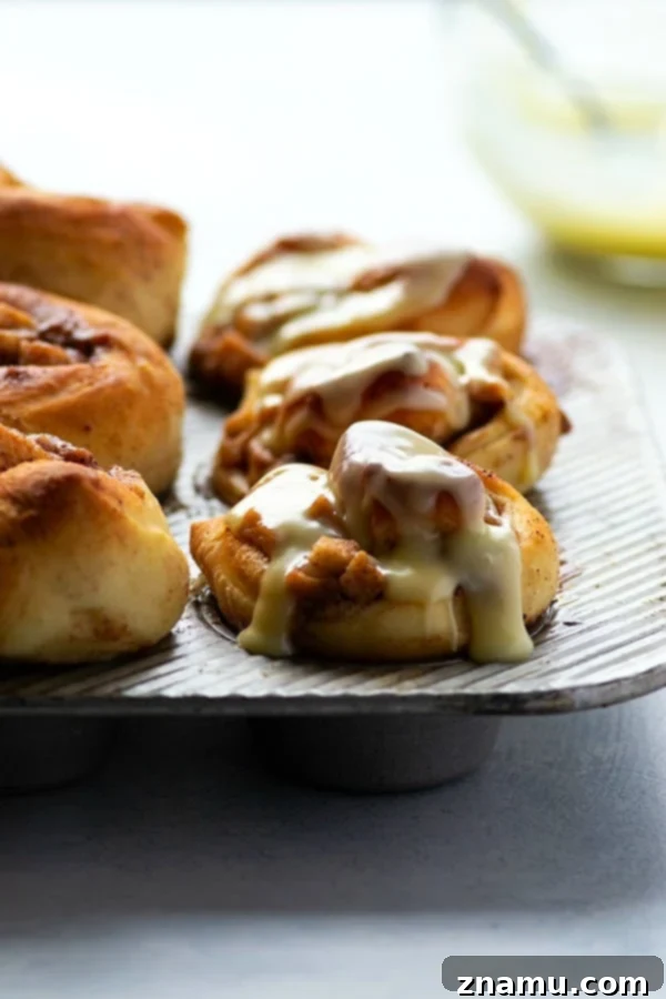 Fluffy cinnamon roll muffins are stuffed with a caramelized apple filling and glazed in a sweet white chocolate glaze for a dreamy fall breakfast!