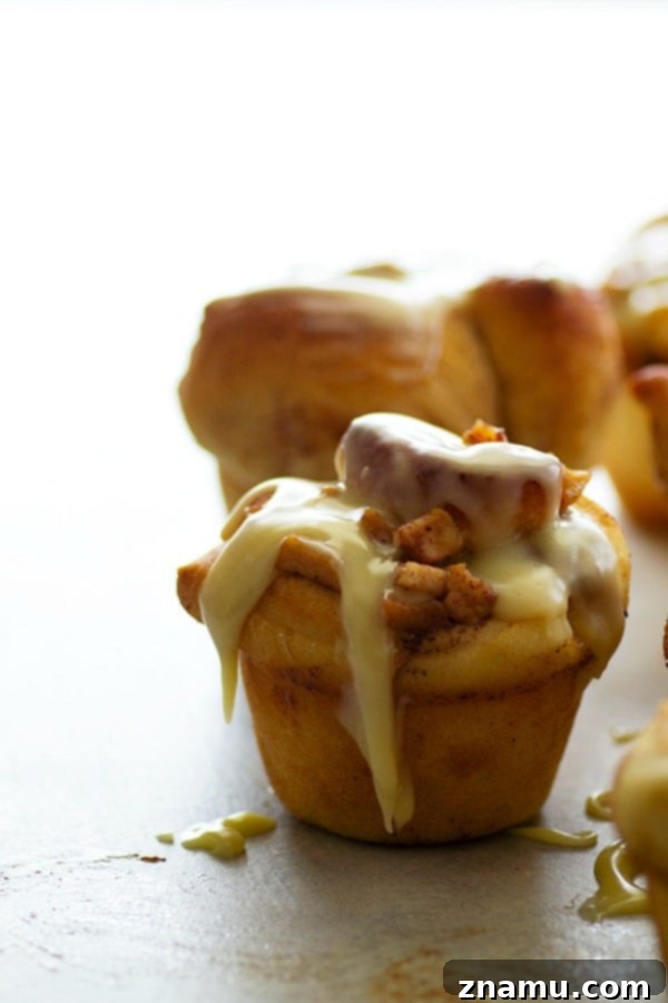 Fluffy cinnamon roll muffins are stuffed with a caramelized apple filling and glazed in a sweet white chocolate glaze for a dreamy fall breakfast!
