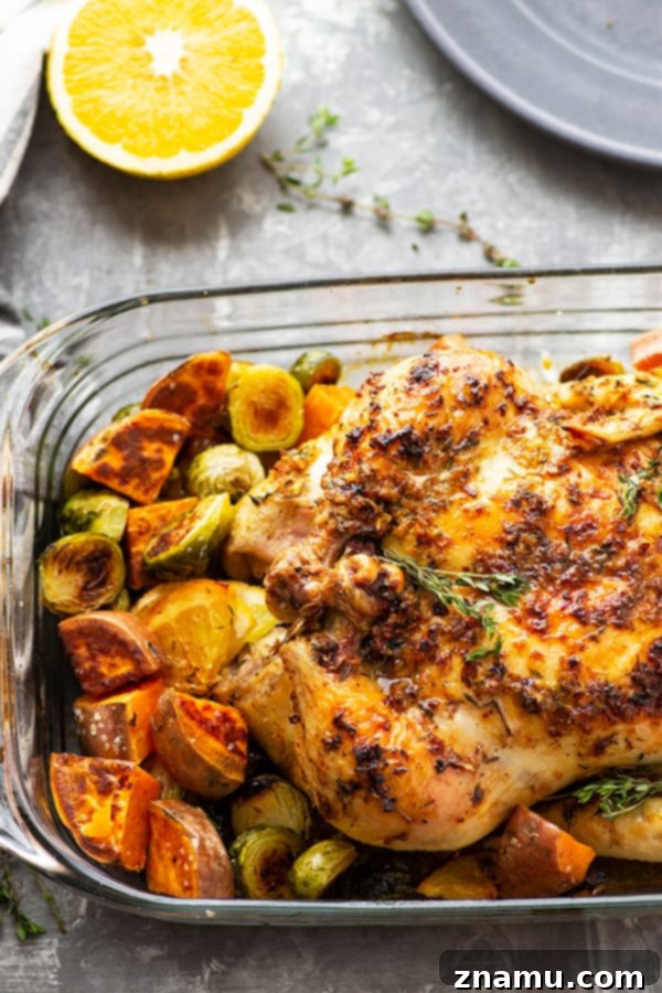 Zesty Ginger Orange Chicken & Roasted Vegetables 3 A beautifully roasted ginger orange chicken, garnished with orange slices and fresh herbs, surrounded by roasted sweet potatoes and Brussels sprouts on a white platter, perfect for a holiday meal.