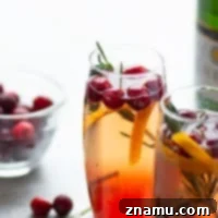 Poinsettia cocktail with cranberries and rosemary garnish.