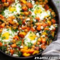 A delicious sweet potato breakfast hash with a baked egg, topped with fresh parsley and feta cheese, served in a cast iron skillet. Highlight of healthy and protein-rich breakfast.
