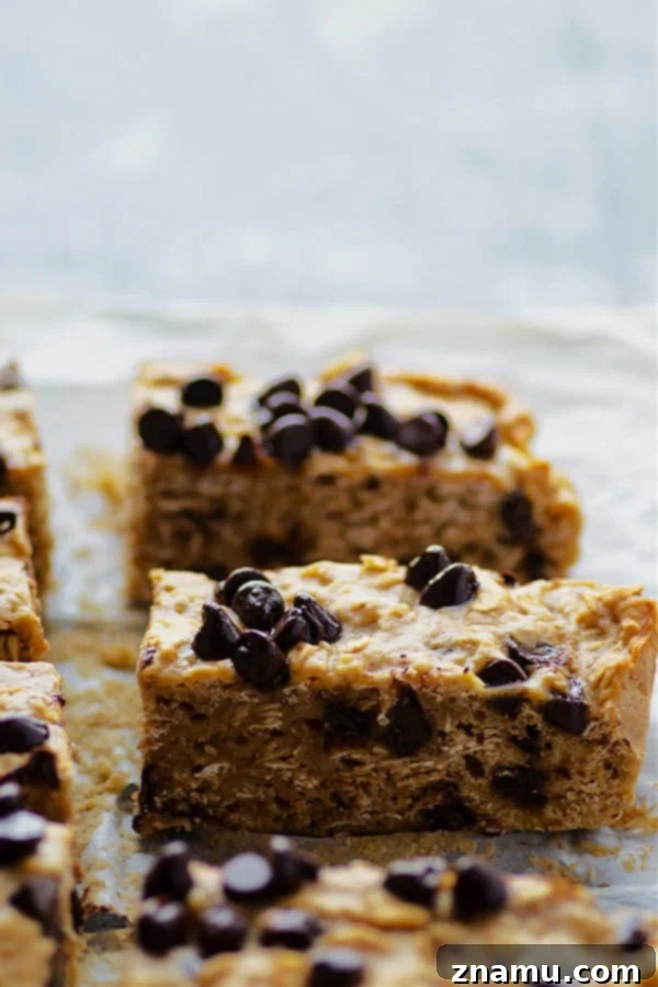 Freshly baked banana chocolate chip oatmeal breakfast bars cooling on a rack, showcasing their thick, chewy texture.