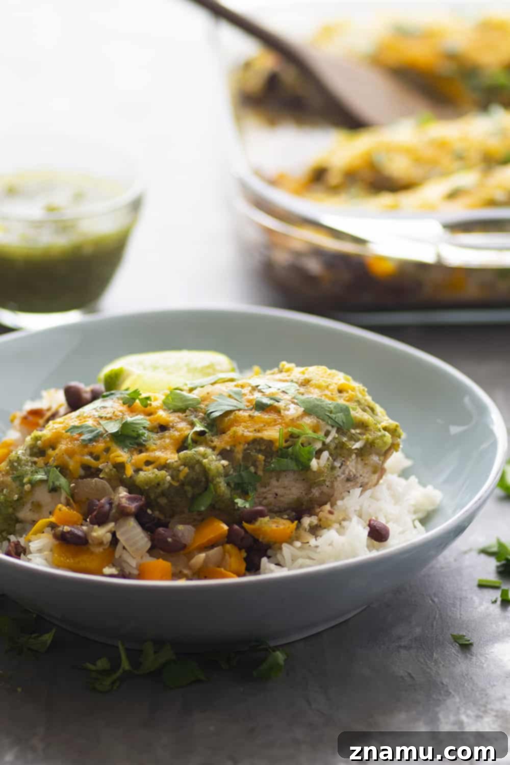 Chicken with Black Bean Salsa Verde 3 Close-up of baked Salsa Verde Chicken, bubbling with cheese and salsa, surrounded by black beans and peppers.