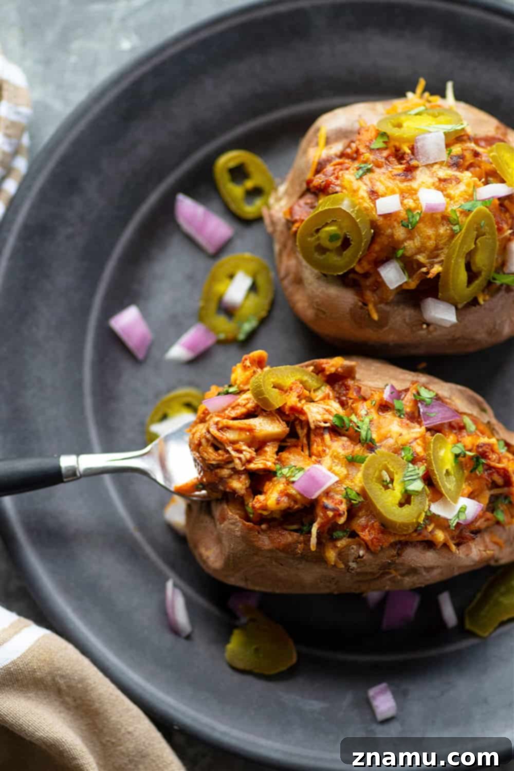 Smoky BBQ Chicken Loaded Sweet Potatoes 5 A top-down view of a fully loaded BBQ Chicken Stuffed Sweet Potato, showcasing the vibrant colors and textures of the barbecue chicken, melted cheese, and fresh toppings.