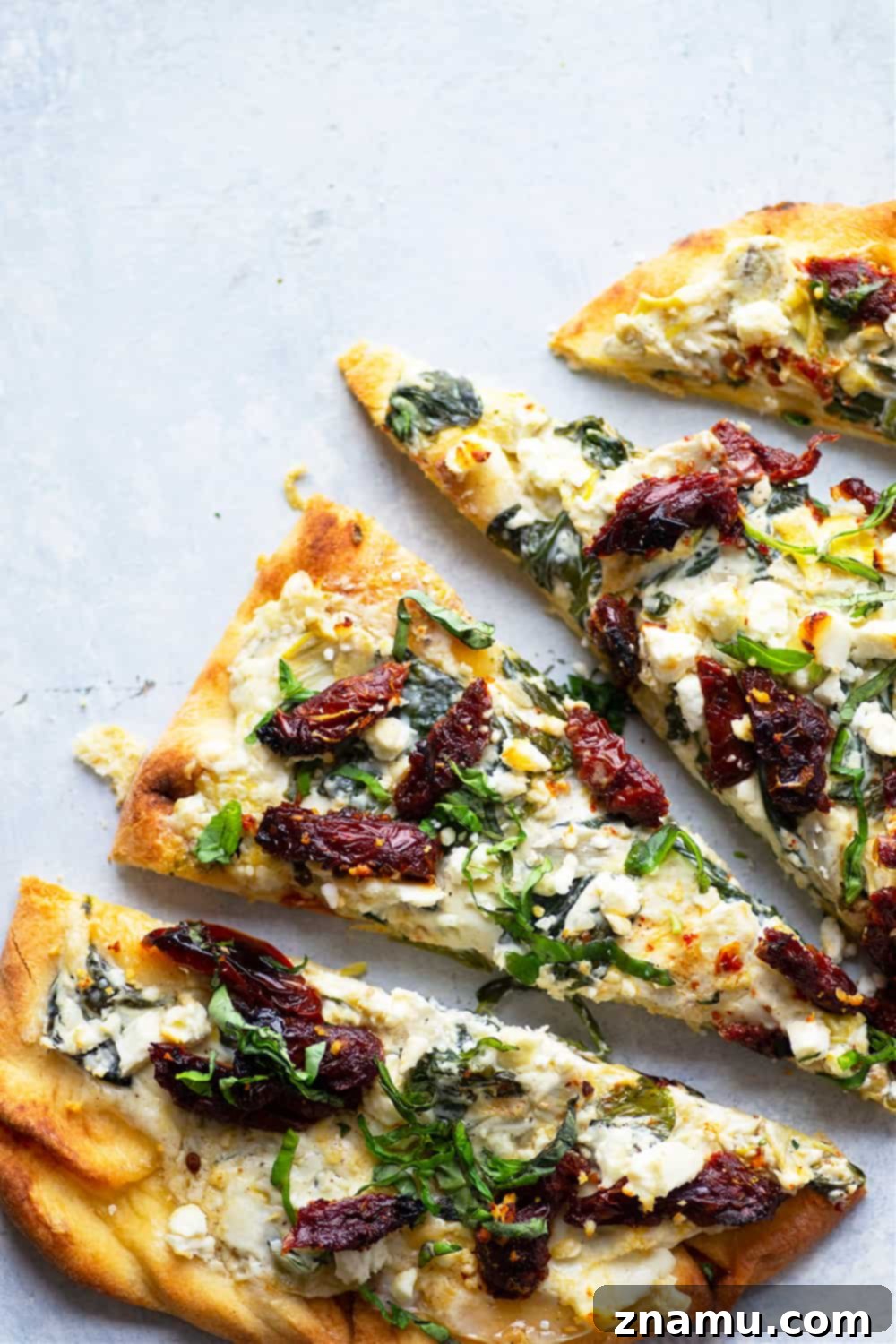 Vibrant Spinach Artichoke Flatbread with Sun-Kissed Tomatoes and Feta 2 A beautifully prepared spinach artichoke flatbread, generously topped with creamy spread, sun-dried tomatoes, and crumbled feta, ready to be served.