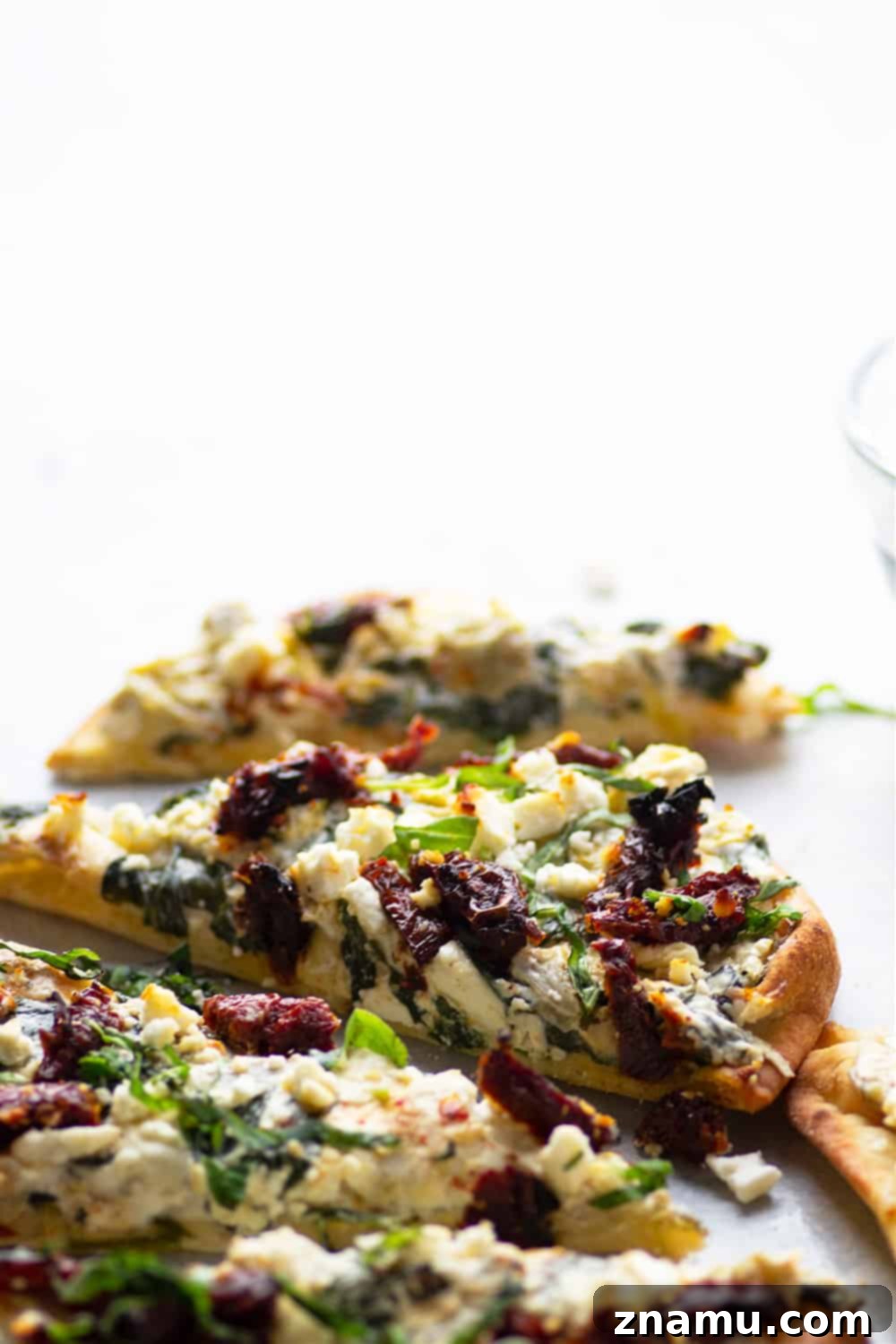 Vibrant Spinach Artichoke Flatbread with Sun-Kissed Tomatoes and Feta 4 Spinach artichoke flatbread garnished with fresh basil, ready for slicing.