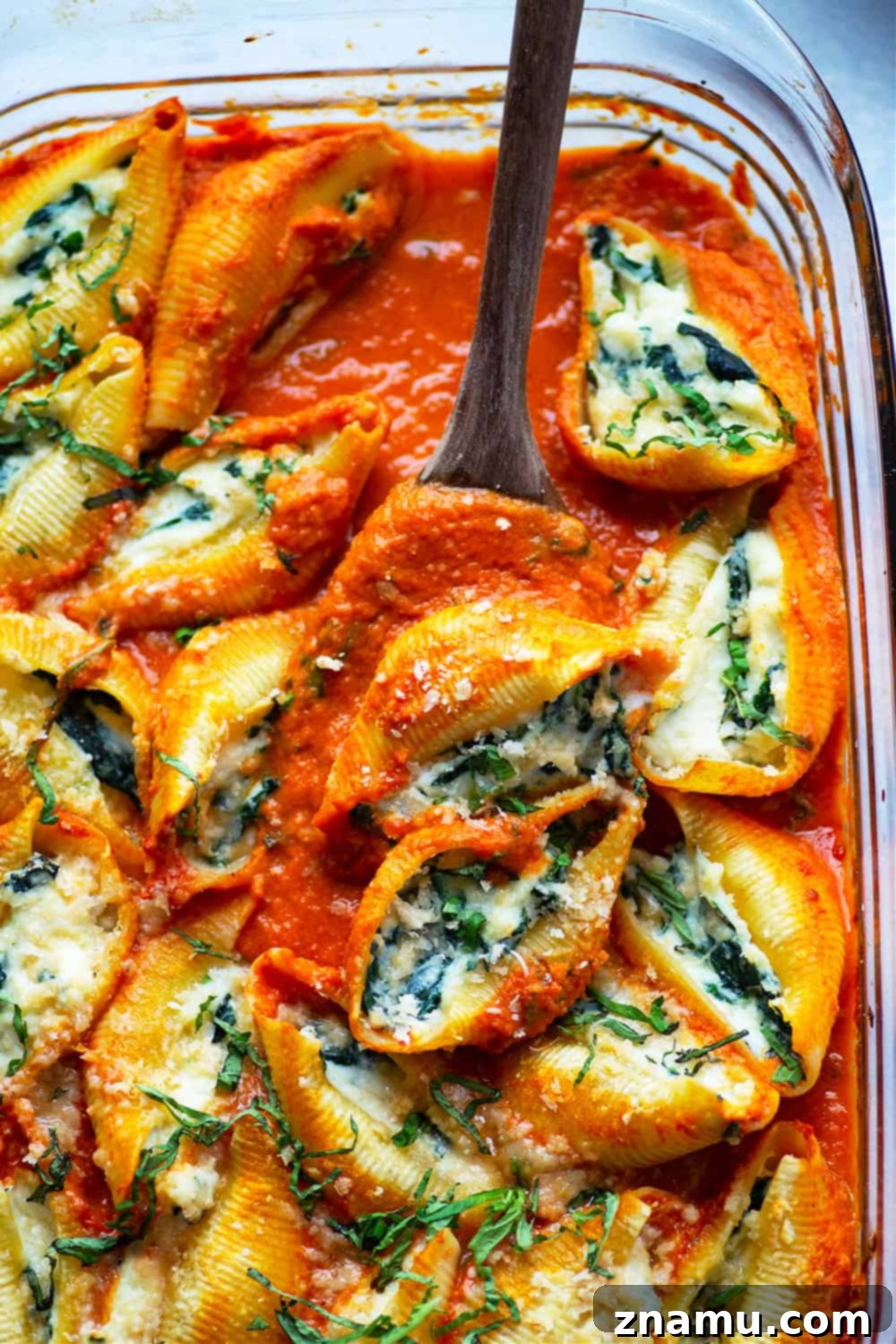 Spinach Ricotta Shells Bathed in Basil Vodka Sauce 3 A large pan of freshly baked spinach ricotta stuffed shells, bubbling with creamy vodka sauce and melted cheese, ready to be served.