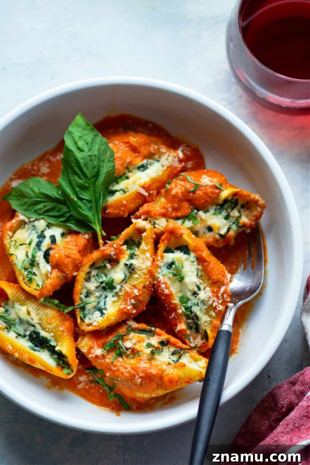 Spinach Ricotta Shells Bathed in Basil Vodka Sauce 4 Close-up of a single spinach ricotta stuffed shell, perfectly golden brown and overflowing with filling, sitting in a vibrant basil vodka sauce.
