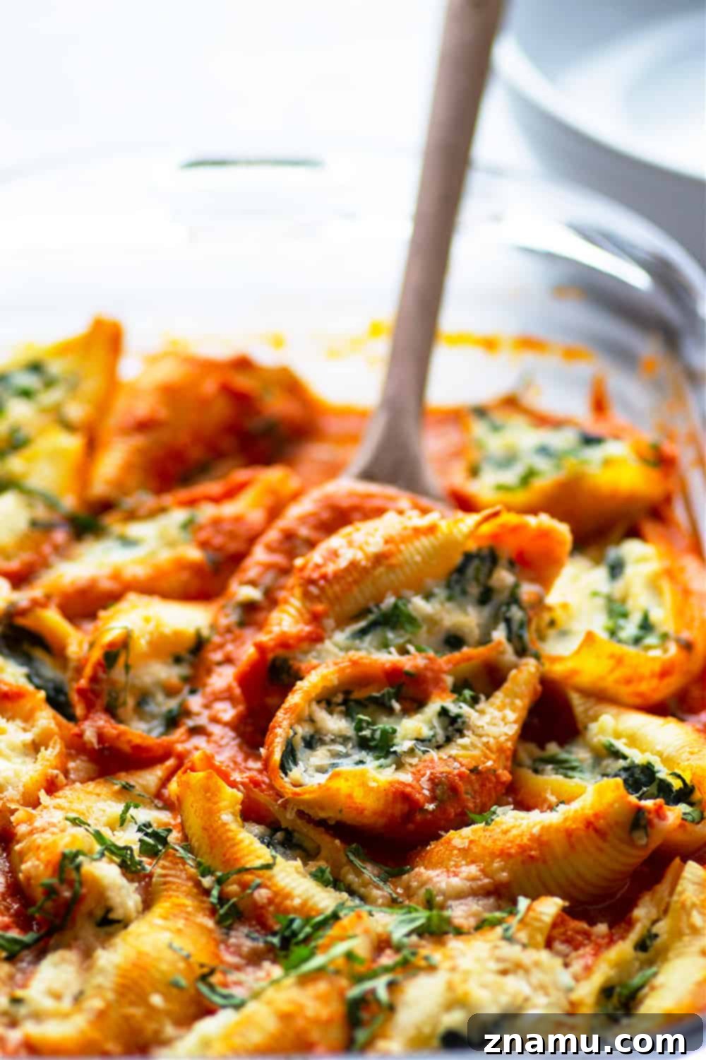 Spinach Ricotta Shells Bathed in Basil Vodka Sauce 5 A close-up shot of several spinach ricotta stuffed shells baking in a dish, with melted cheese and bubbling basil vodka sauce.