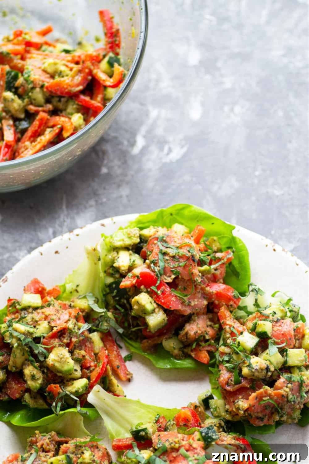 Ingredients for Smoked Salmon Lettuce Wraps laid out on a table, including salmon, vegetables, and pesto ingredients.