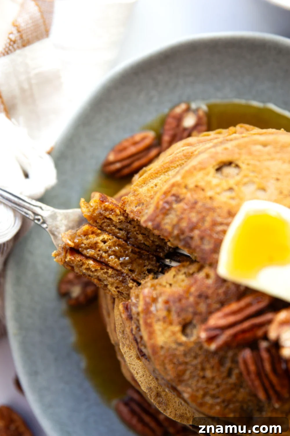 Cozy Gingerbread Pancakes 6 A beautifully plated stack of gingerbread pancakes, adorned with maple syrup and toasted pecans, ready to be enjoyed.
