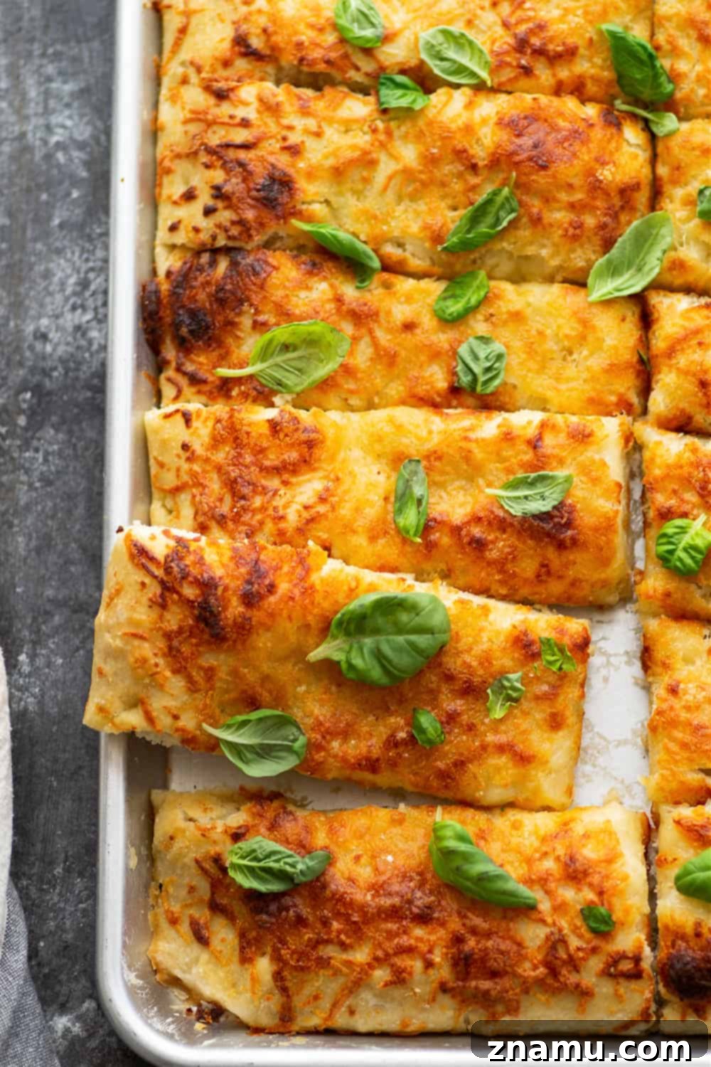 Savory Cheese Focaccia Sticks 3 Hands reaching for a fluffy slice of homemade Pizza Focaccia Breadsticks on a baking sheet, showcasing its soft interior.