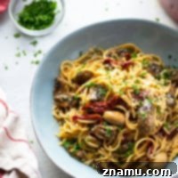 Sundried Tomato & Mushroom Carbonara 7 A plate of Sun-Dried Tomato Mushroom Carbonara, garnished with fresh herbs and Parmesan.