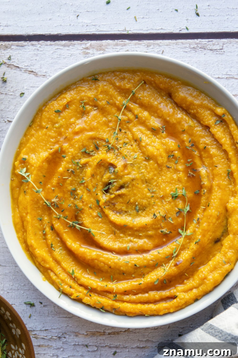 Creamy Maple Butternut Mash 3 Overhead view of a serving of maple mashed butternut squash in a bowl, with a spoon resting in it, ready to be enjoyed.