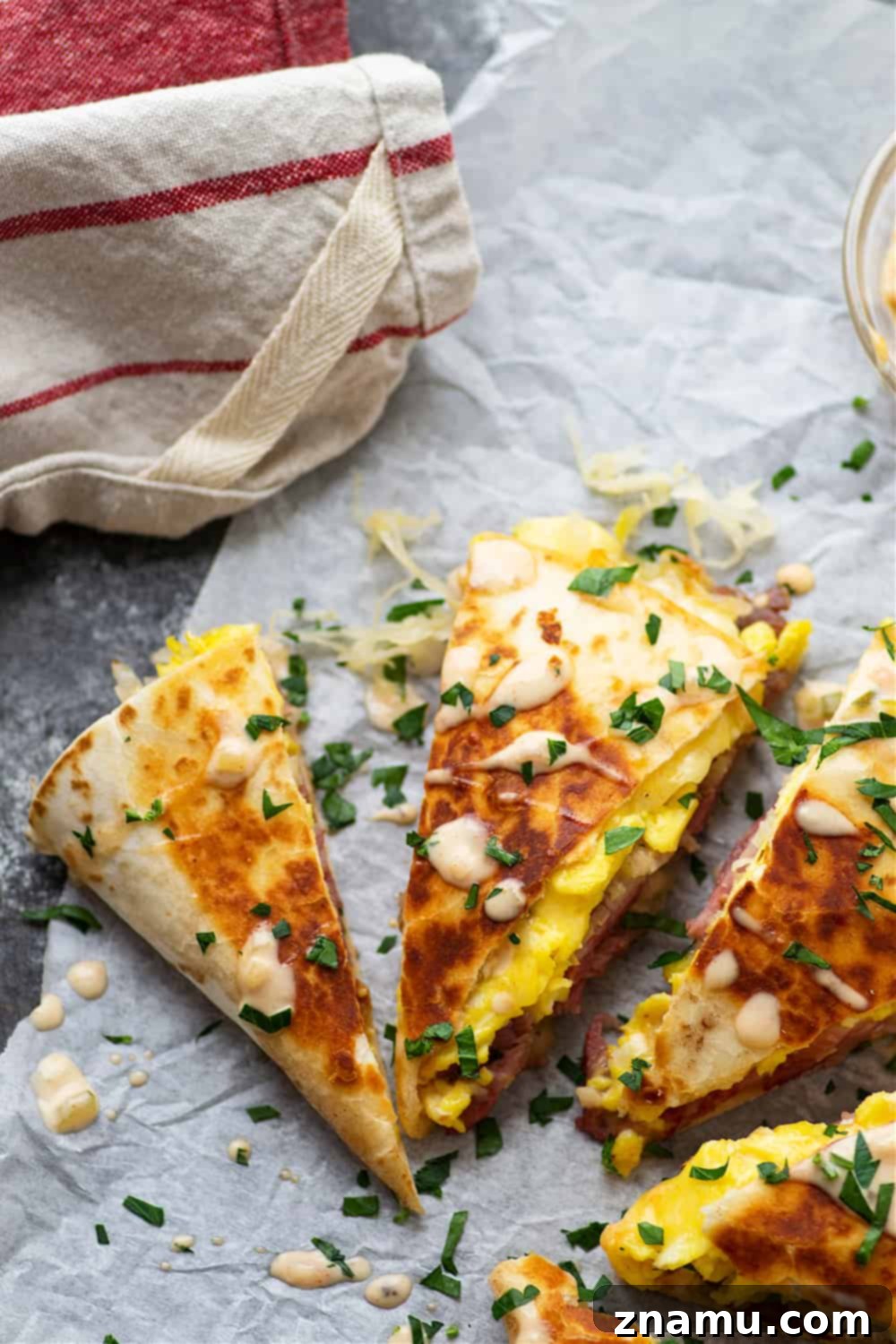 Rise and Shine Corned Beef Quesadillas 5 Stacked breakfast corned beef quesadilla wedges garnished with fresh parsley and a drizzle of Thousand Island dressing.
