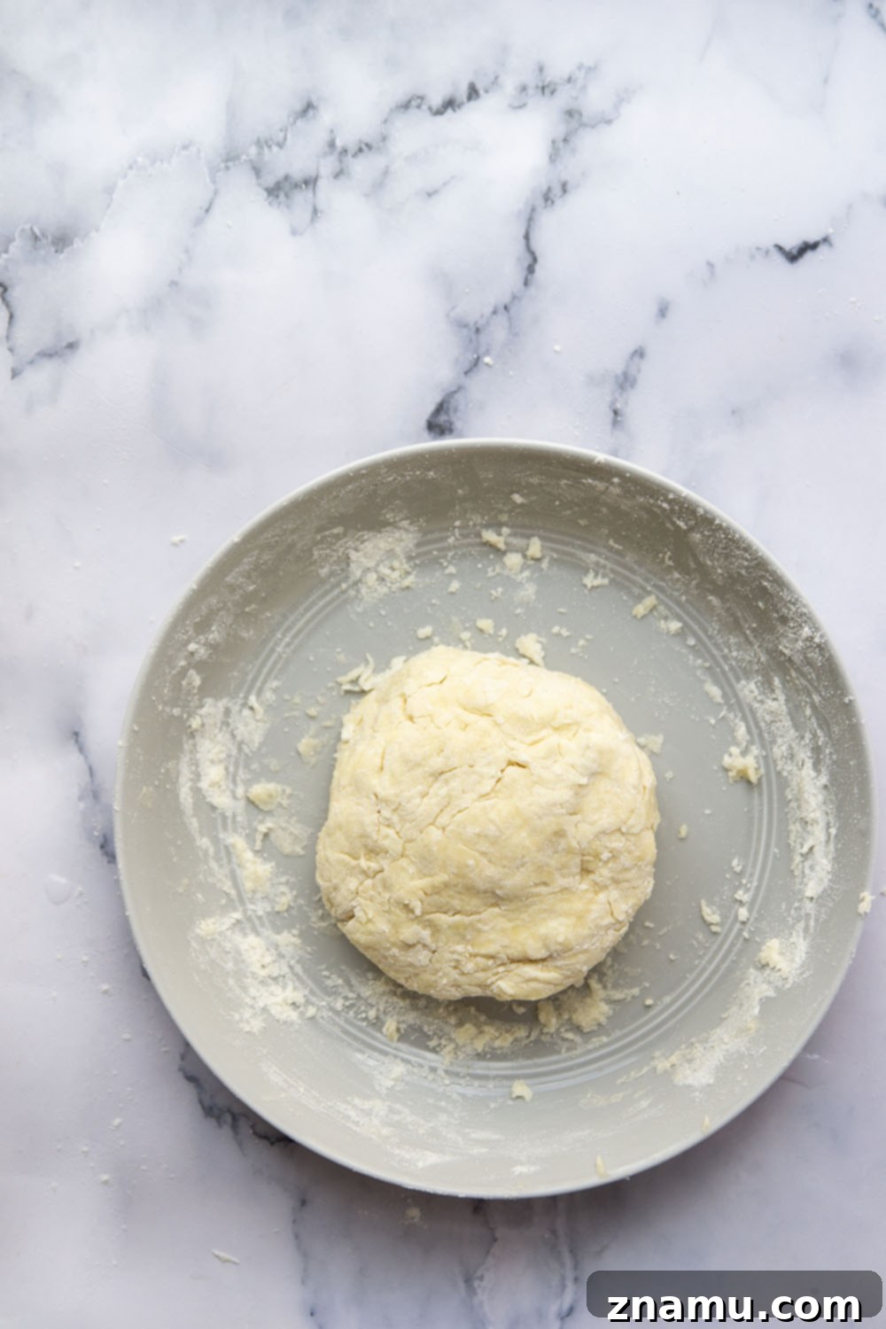 Foolproof Pie Crust 5 Hands pressing butter into flour in a mixing bowl with a pastry cutter.