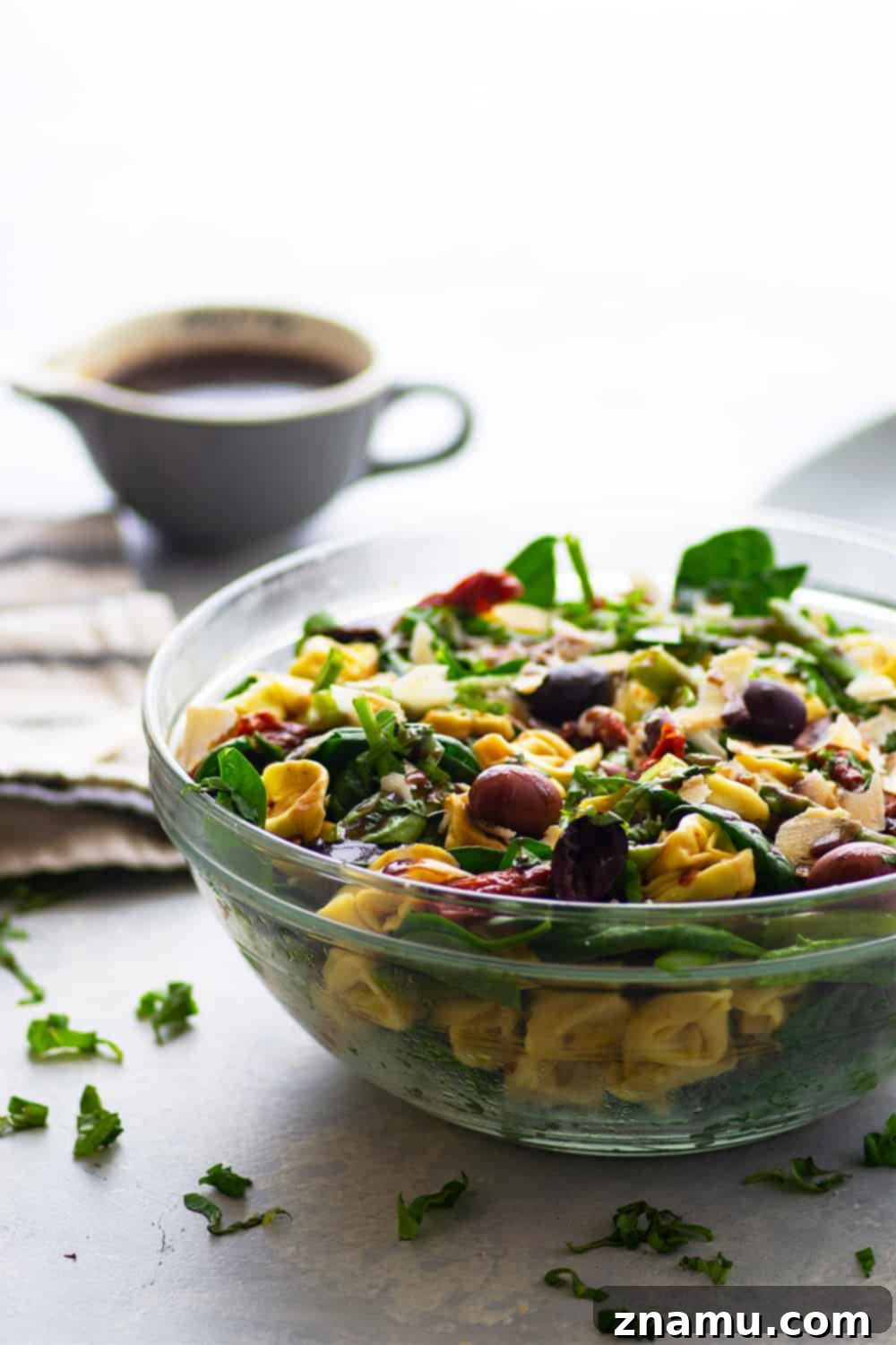 Close-up of Tuscan Tortellini Salad showing cheese-filled pasta, sun-dried tomatoes, and fresh spinach.