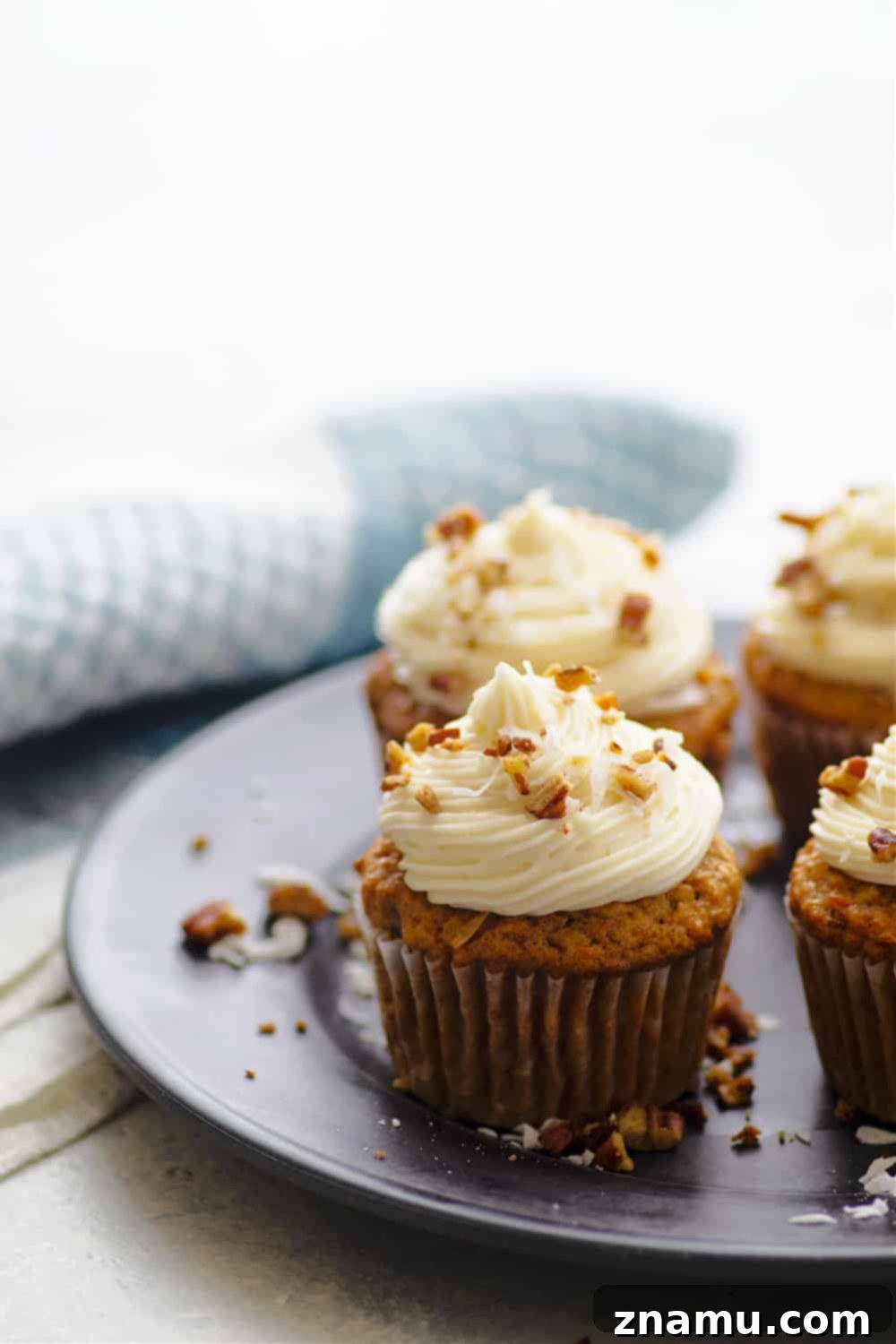 A trio of Coconut Carrot Cake Cupcakes showcasing their generous frosting and garnish.