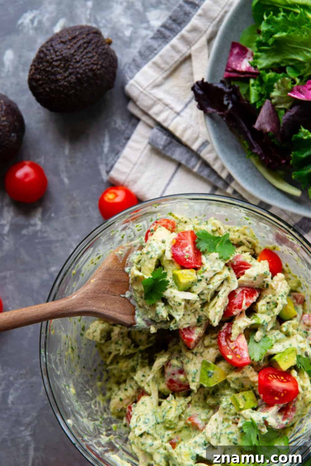 Emerald Goddess Chicken Salad 2 A vibrant bowl of Green Goddess Chicken Salad with shredded chicken, cherry tomatoes, and avocado, topped with fresh herbs.