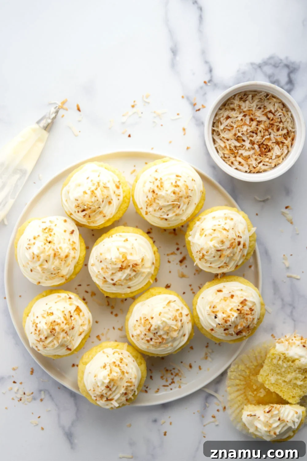 Heavenly Coconut Cupcakes with Cream Cheese Frosting 4 A plate of freshly baked coconut cupcakes adorned with cream cheese frosting