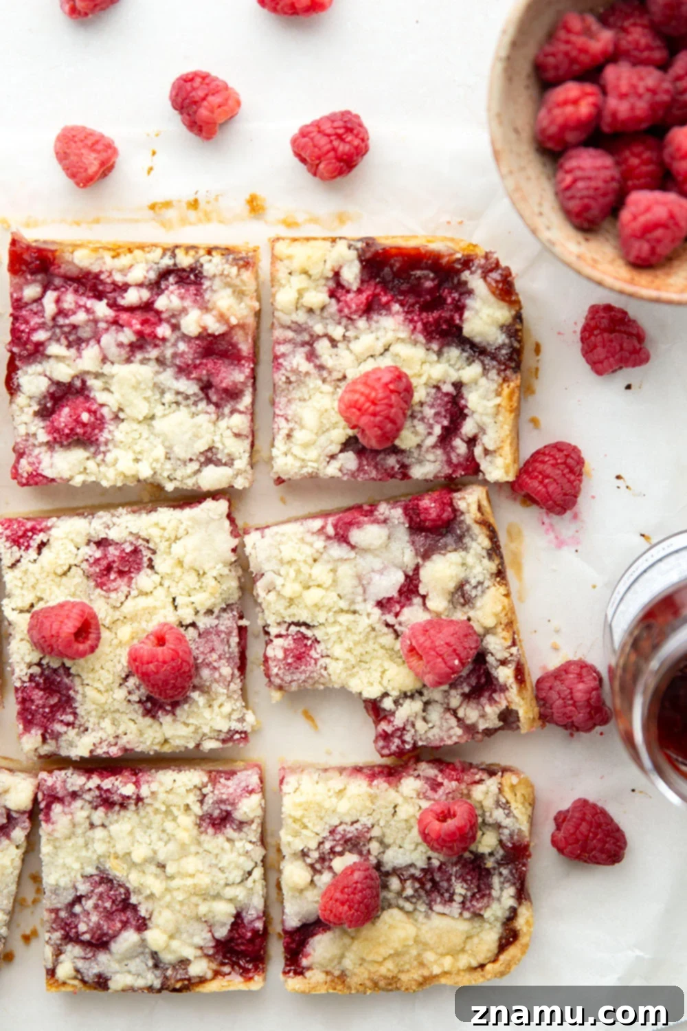 Crimson Shortbread Delights 6 Hand holding a piece of raspberry shortbread bar, highlighting the crumbly top and fruit filling.