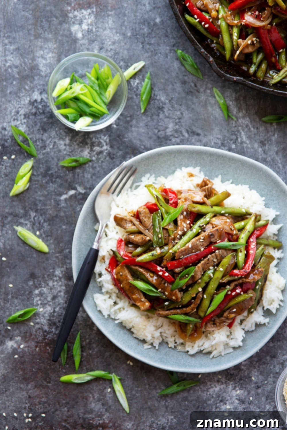 Sticky Ginger-Black Pepper Beef 3 Close-up of freshly prepared black pepper beef stir fry with green beans, bell peppers, and scallions in a serving dish.