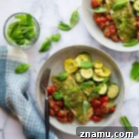 Baked entirely on one sheet pan and smothered in flavorful arugula pesto, this bursting tomato pesto salmon and zucchini is the perfect weeknight dinner to use up an abundance of veggies!