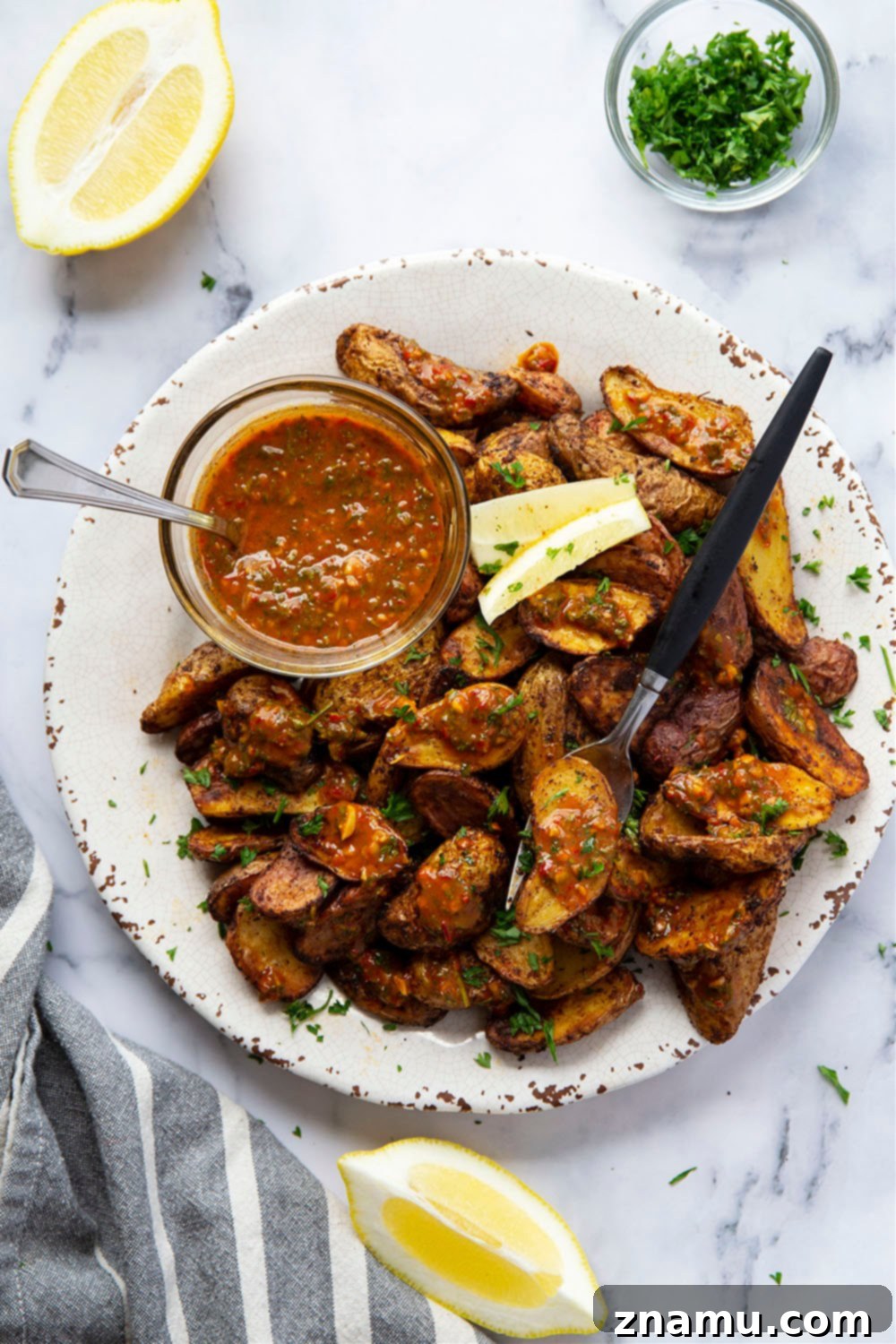 Crispy Air Fryer Fingerling Potatoes with Zesty Harissa Chimichurri 6 Air fryer fingerling potatoes in a serving bowl, garnished with fresh herbs and lemon.
