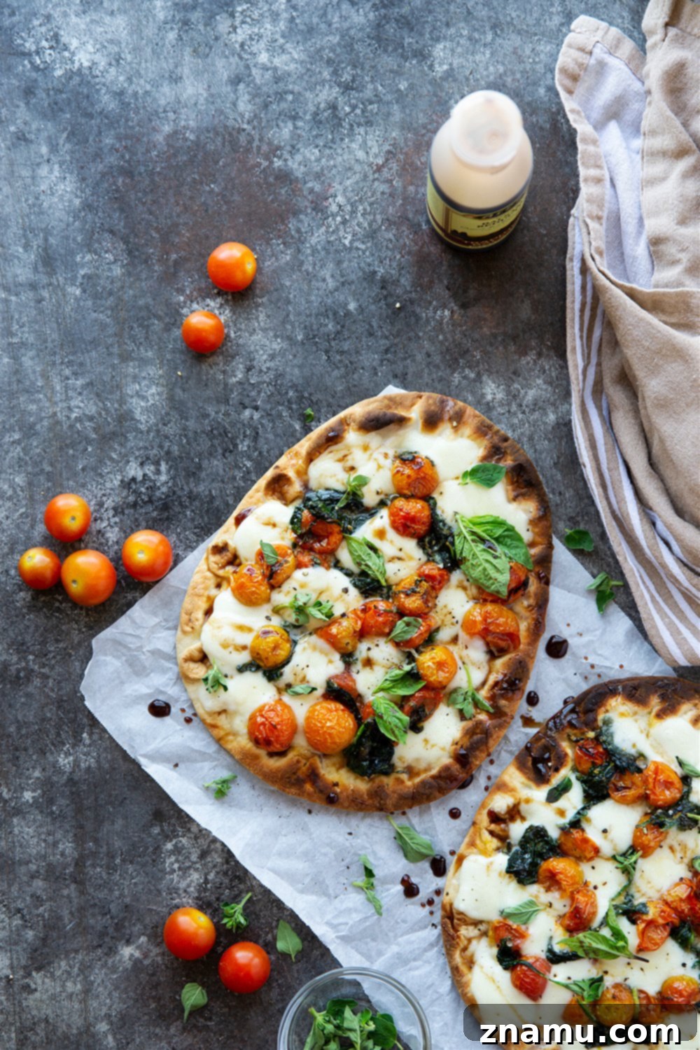 Creamy Burrata Flatbread with Burst Tomatoes and Spinach 3 Close-up of bursting tomato flatbread featuring roasted cherry tomatoes and melted burrata cheese.