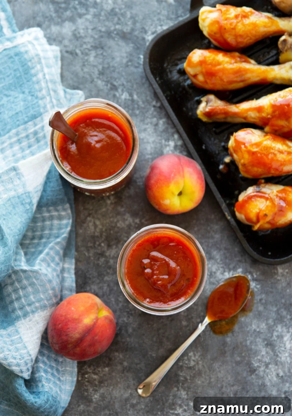 Sweet Heat Peach Chipotle Glaze 2 A jar of homemade Chipotle Peach BBQ Sauce with fresh peaches and chipotle peppers in the background.